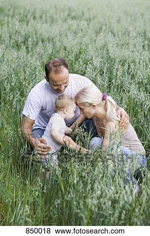 Stock Photo - Two parents with their daughter in a field. Fotosearch