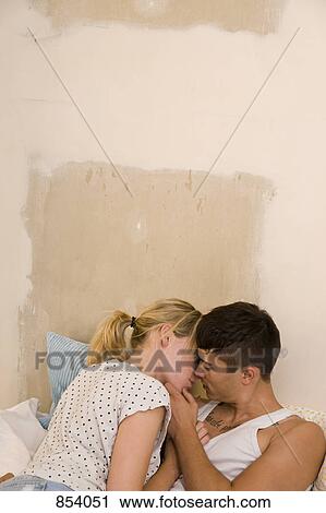 Stock Image - A young couple in bed about to kiss. Fotosearch