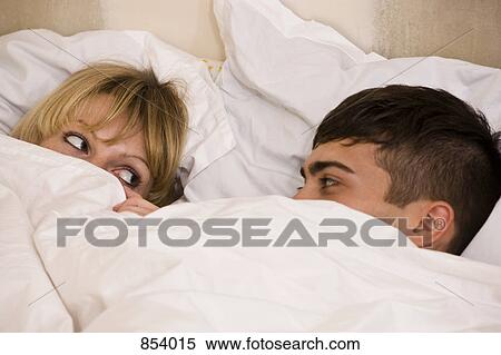 A young couple in bed with the duvet pulled up to their eyes View Large Photo Image Stock Photography - A young couple in bed with the duvet pulled up to their eyes. Fotosearch