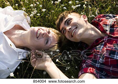 A young couple lying in on their backs in grass, close-up View Large Photo Image Picture - A young couple lying in on their backs in grass, close-up. Fotosearch