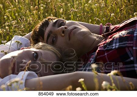 A young couple lying on their backs in a field View Large Photo Image Stock Photo - A young couple lying on their backs in a field. Fotosearch