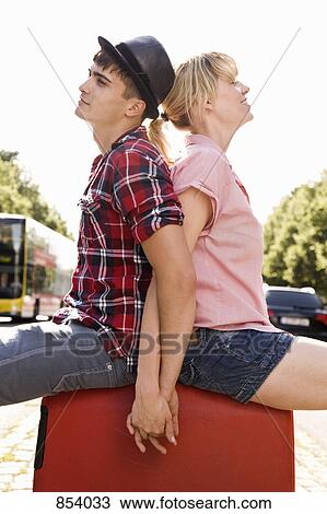 Stock Image - A young couple sitting on a suitcase. Fotosearch