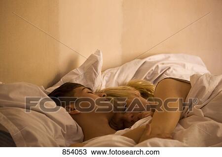 A young couple sleeping in bed View Large Photo Image Stock Image - A young couple sleeping in bed. Fotosearch