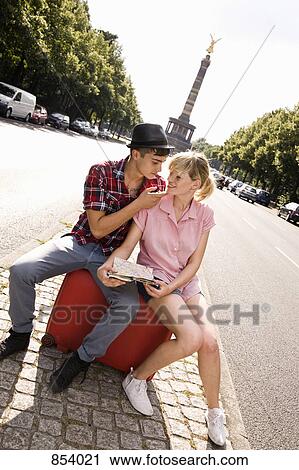 Stock Image - A young couple with a suitcase and a map with the Berlin Victory Column in background. Fotosearch