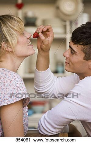 A young man holding a strawberry flirtatiously for a young woman View Large Photo Image Stock Image - A young man holding a strawberry flirtatiously for a young woman. Fotosearch