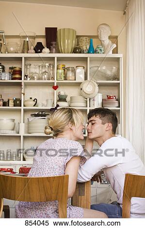 Stock Photography - A young passionate couple in sitting in a domestic kitchen. Fotosearch
