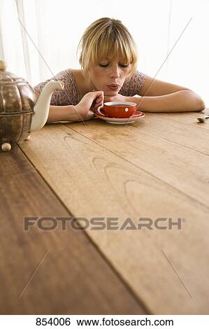 A young woman blowing on a tea cup View Large Photo Image Stock Photograph - A young woman blowing on a tea cup. Fotosearch