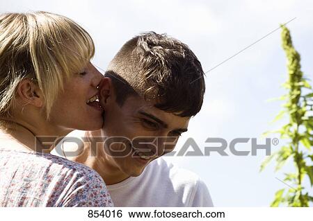 A young woman playfully licking a young man's ear View Large Photo Image Stock Photograph - A young woman playfully licking a young man's ear . Fotosearch
