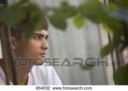 Stock Image - Portrait of a young man day dreaming. Fotosearch