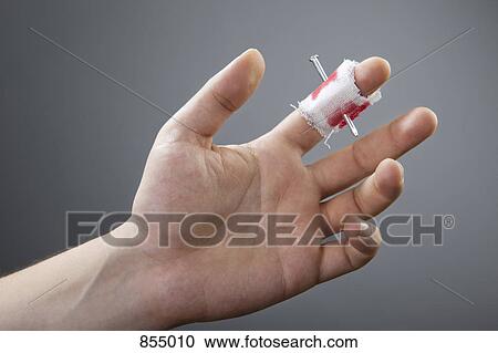 Stock Image - A nail piercing a finger. Fotosearch