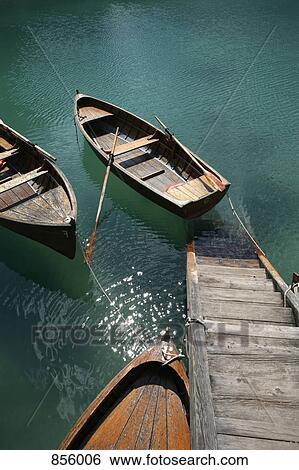 Stock Photograph - Steps down to wooden boats floating on water, Braies Lake, South Tyrol, Italy. Fotosearch