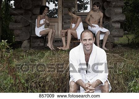 A man sitting in grass and three people in towels in the background (focus on foreground) View Large Photo Image Stock Photo - A man sitting in grass and three people in towels in the background (focus on foreground). Fotosearch