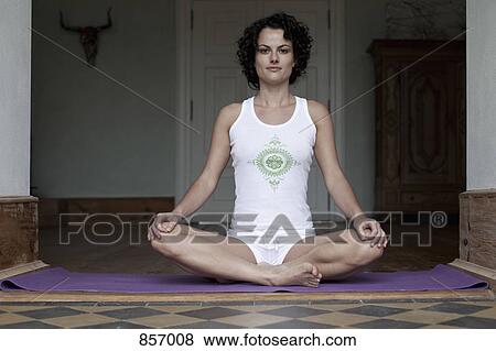 A woman sitting cross-legged on a yoga mat View Large Photo Image Stock Photo - A woman sitting cross-legged on a yoga mat. Fotosearch