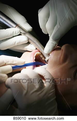 Stock Image - Close-up of a dentist and a dental assistant working on a female patient. Fotosearch