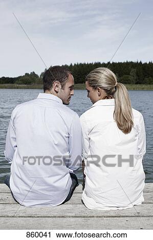 A couple sitting on a jetty View Large Photo Image Stock Image - A couple sitting on a jetty. Fotosearch