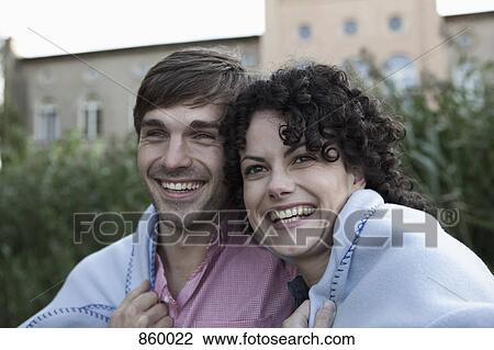A couple wrapped together in a blanket, laughing View Large Photo Image Stock Image - A couple wrapped together in a blanket, laughing. Fotosearch