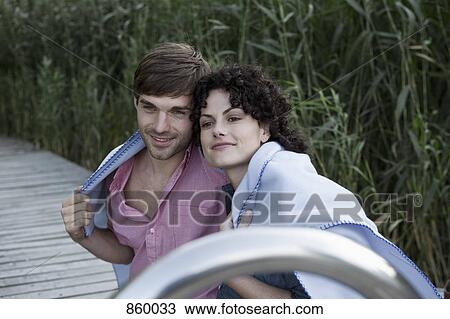 Stock Image - A couple wrapped together in a blanket. Fotosearch
