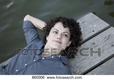 A woman lying on a jetty View Large Photo Image Stock Photograph - A woman lying on a jetty. Fotosearch