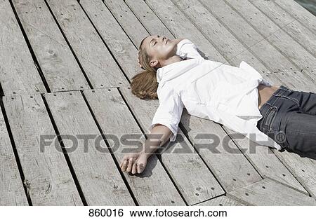 A woman lying on a wood deck View Large Photo Image Stock Photograph - A woman lying on a wood deck. Fotosearch