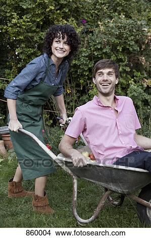 Picture - A woman pushing a man in a wheelbarrow. Fotosearch