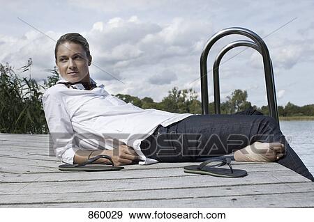 Stock Photo - A woman relaxing on a jetty. Fotosearch