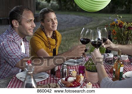 Four people at a dinner raising their wineglasses in a toast View Large Photo Image Stock Image - Four people at a dinner raising their wineglasses in a toast. Fotosearch