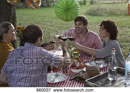 Four people at a dinner raising their wineglasses in a toast View Large Photo Image Stock Photo - Four people at a dinner raising their wineglasses in a toast. Fotosearch