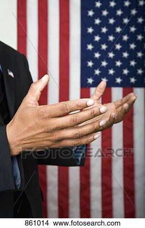 Detail of a man gesturing in front of an American flag View Large Photo Image Picture - Detail of a man gesturing in front of an American flag. Fotosearch
