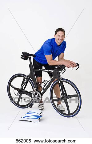 Stock Photography - A man standing with a racing bike. Fotosearch