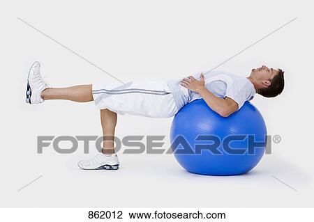 Stock Image - A man stretching with an exercise ball. Fotosearch