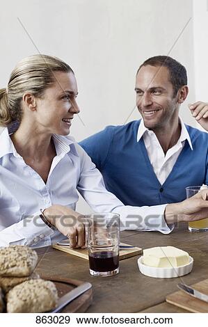 A couple sitting together at a dining table and smiling View Large Photo Image Stock Photo - A couple sitting together at a dining table and smiling. Fotosearch