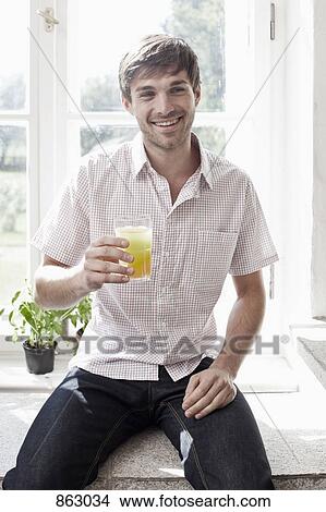 A man holding a glass of juice and smiling View Large Photo Image Picture - A man holding a glass of juice and smiling. Fotosearch