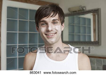 Stock Image - A man using a face mask in the bathroom. Fotosearch