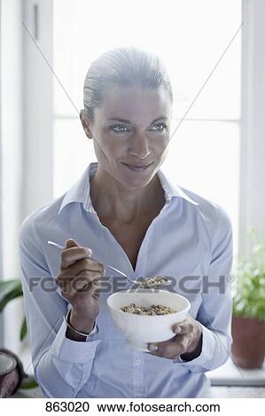 Stock Image - A woman eating a bowl of cereal . Fotosearch
