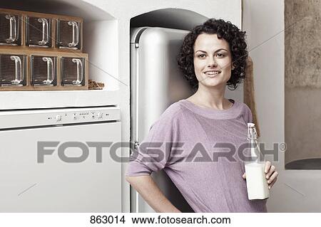A woman holding a bottle of milk in the kitchen View Large Photo Image Picture - A woman holding a bottle of milk in the kitchen. Fotosearch