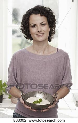 Stock Image - A woman holding a bowl of rice. Fotosearch