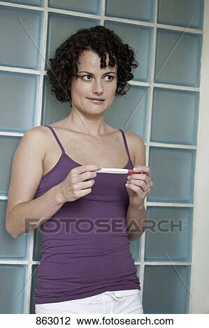 Stock Image - A woman holding a pregnancy test. Fotosearch