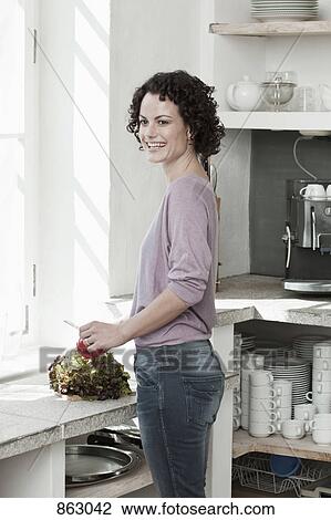 Stock Image - A woman preparing vegetables in the kitchen. Fotosearch
