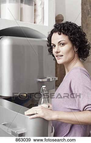A woman putting milk in the fridge View Large Photo Image Stock Photo - A woman putting milk in the fridge. Fotosearch