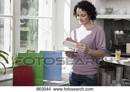 Picture - A woman standing next to gift bags and looking at cards. Fotosearch
