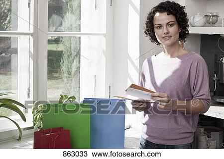 Stock Image - A woman standing with gift bags and cards. Fotosearch