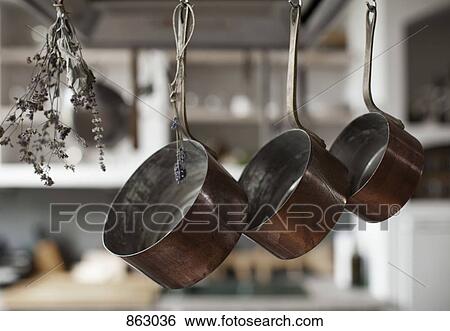 Stock Photograph - Three saucepans hanging from hooks with dried lavender. Fotosearch