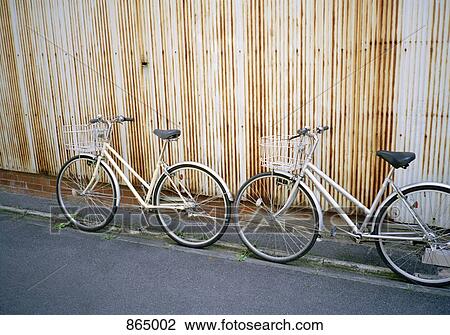 Two bicycles leaning on a wall View Large Photo Image Stock Image - Two bicycles leaning on a wall. Fotosearch