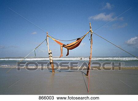Stock Image - A man lying in a hammock on a beach. Fotosearch