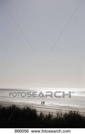 A view of two people walking on the beach View Large Photo Image Stock Photograph - A view of two people walking on the beach. Fotosearch