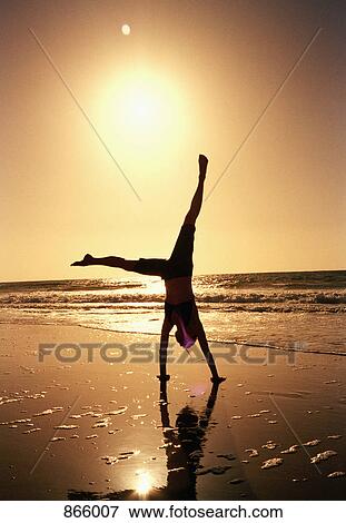 A woman doing a cartwheel on a beach at sunset View Large Photo Image Stock Photo - A woman doing a cartwheel on a beach at sunset. Fotosearch