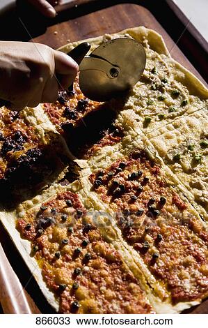 Stock Image - Detail of a pizza being cut. Fotosearch
