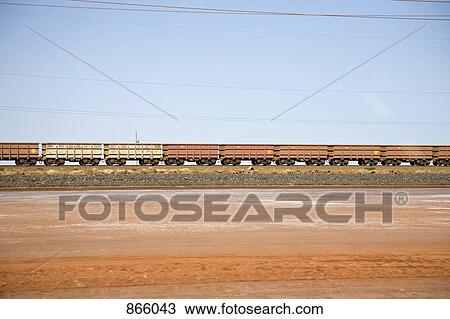 Stock Image - Freight train moving through a desert landscape. Fotosearch