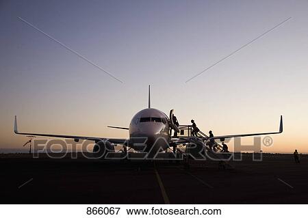 Stock Photo - People boarding an airplane at dusk. Fotosearch