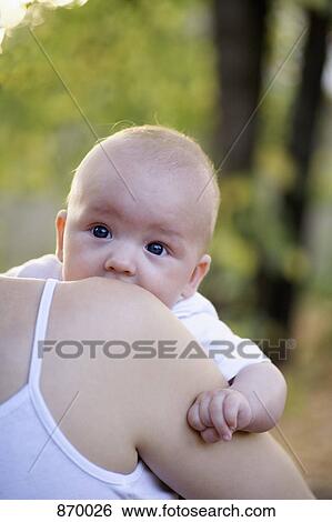 Stock Photograph - A baby boy being carried by his mother, over the shoulder view. Fotosearch